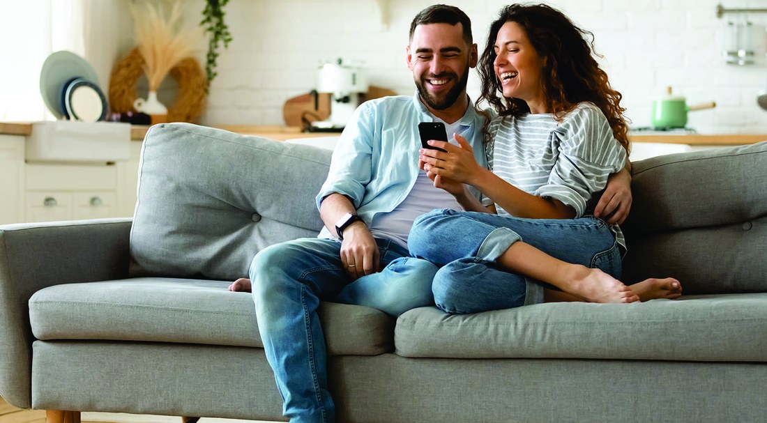 Casal sentado no sofá do living, conversando.