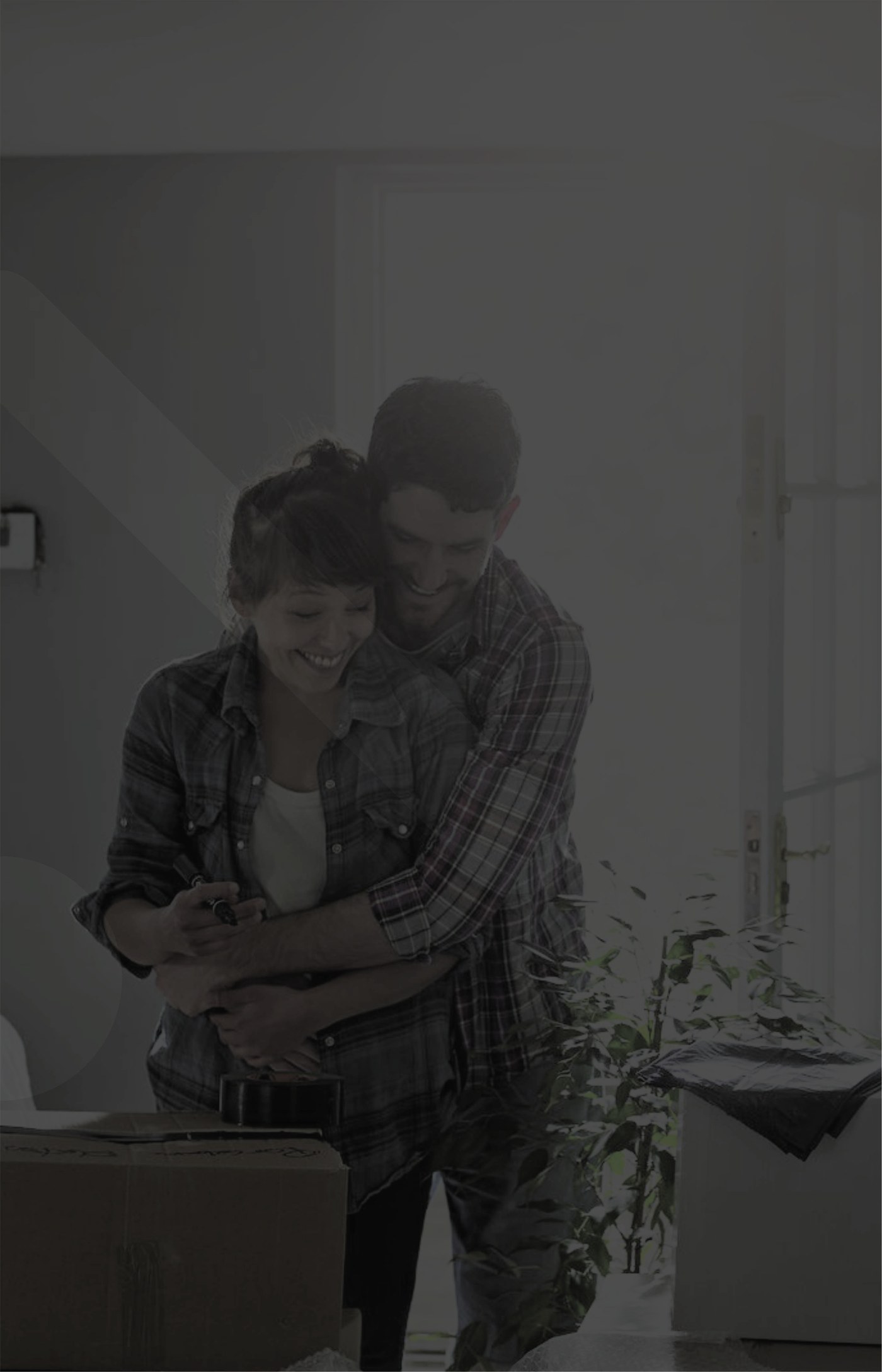 Casal abraçado entre caixas de mudança no dia de entrar no novo apartamento.